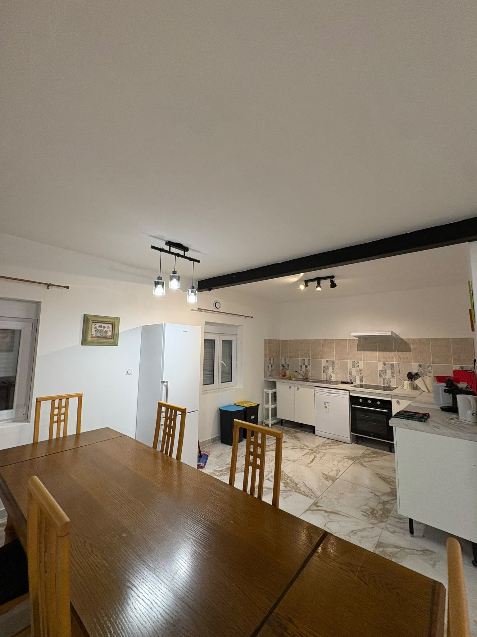 A compact kitchen with a dining area, white appliances, and a marble floor.