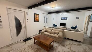 A living room with a sofa, coffee table, and a television.