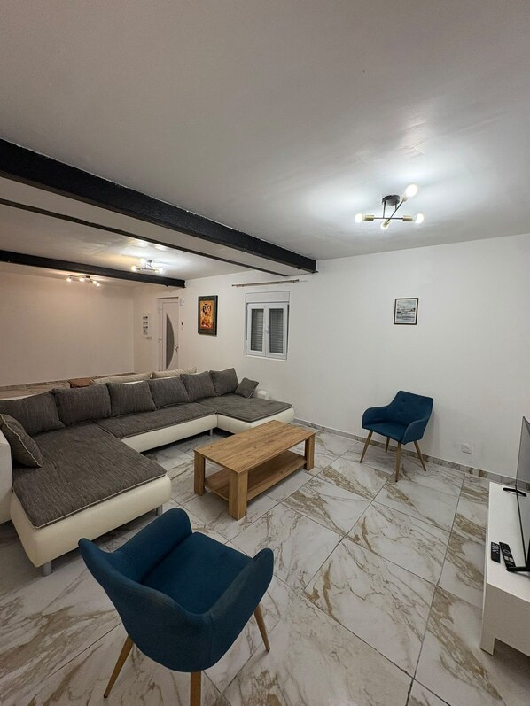 Een woonkamer met een hoekbank, een salontafel en twee fauteuils.