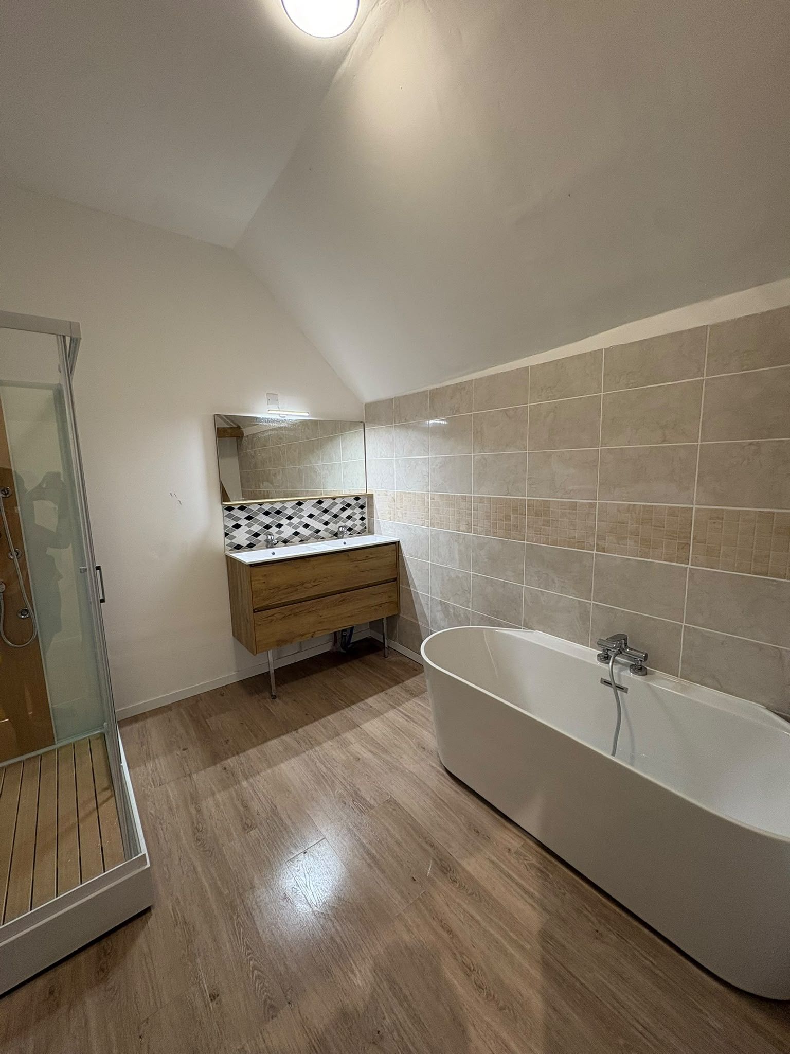 Un bagno moderno con cabina doccia, vasca da bagno indipendente e un mobile lavabo con schienale in piastrelle.