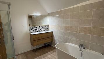 Un bagno moderno con cabina doccia, vasca da bagno indipendente e un mobile lavabo con schienale in piastrelle.