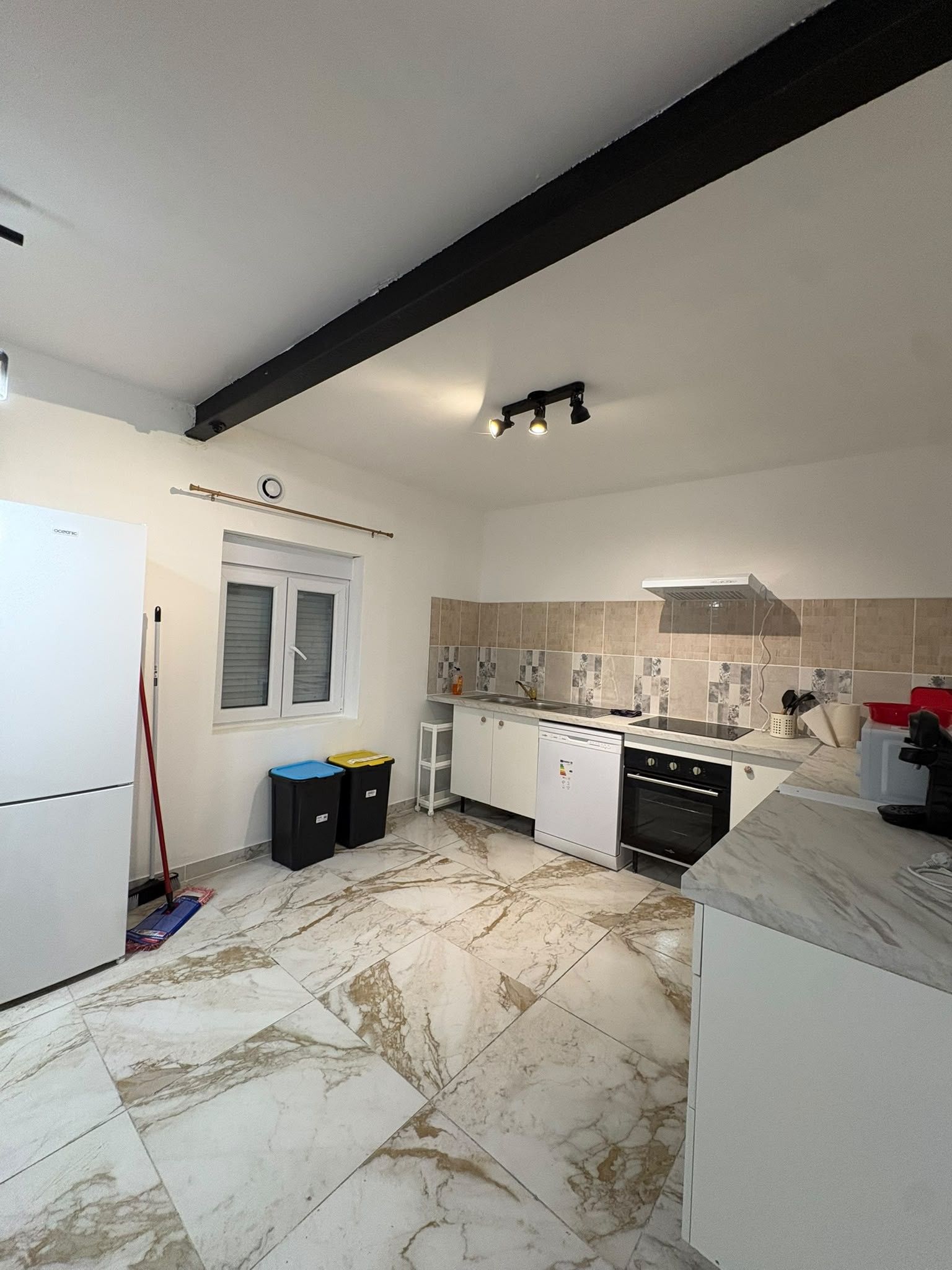 A kitchen with a refrigerator, oven, and tiled backsplash.