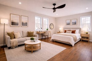 Une chambre à coucher avec un lit, un bureau, un canapé et un ventilateur de plafond.