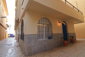 A building with a tiled ground floor, a blue door, and a window with metal bars. - Stylish Mediterranean Duplex Near the Beach (Torremolinos)
