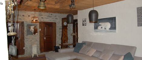 Un accogliente soggiorno con un divano ampio, un soffitto in legno, un orologio e un quadro appeso al muro raffigurante un orso polare.