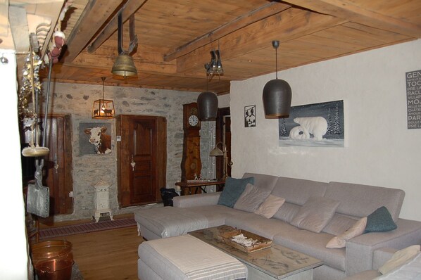 A cozy living room with a large sofa, a wooden ceiling, a clock, and a wall-mounted picture of a polar bear.