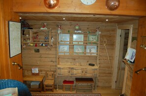 A wooden room with a wooden cabinet, a small table, a chair, a clock, and a map on the wall.