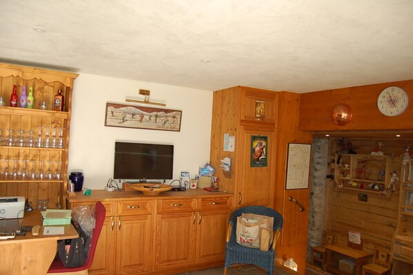 A room with wooden cabinets, a television, a chair, and various items on shelves.