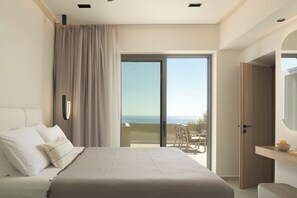 Une chambre à coucher avec un lit, une vue sur la mer et un balcon équipé de chaises.