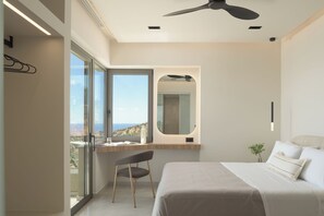 A bedroom with a bed, a desk, a chair, a large window, and a ceiling fan. - Aelia Private Villa Triopetra (Unknown)