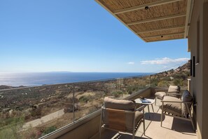 Un balcon avec vue sur la mer et un paysage montagneux.