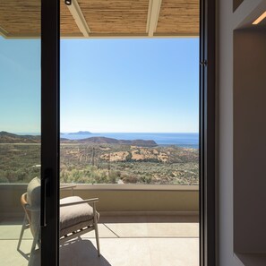 Un balcon offrant une vue sur un paysage vallonné et la mer.