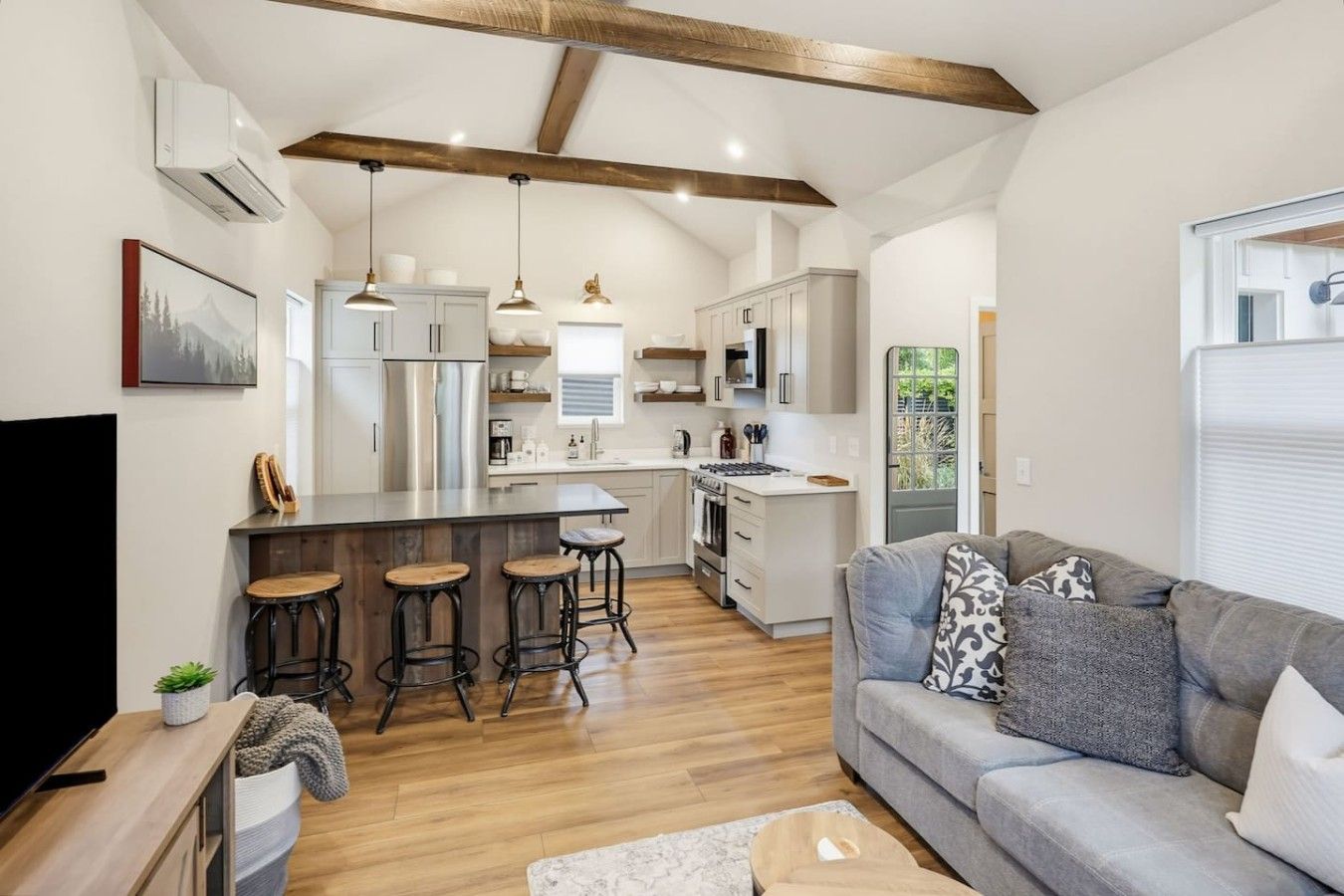 A modern kitchen with a central island, bar stools, and a built-in oven.