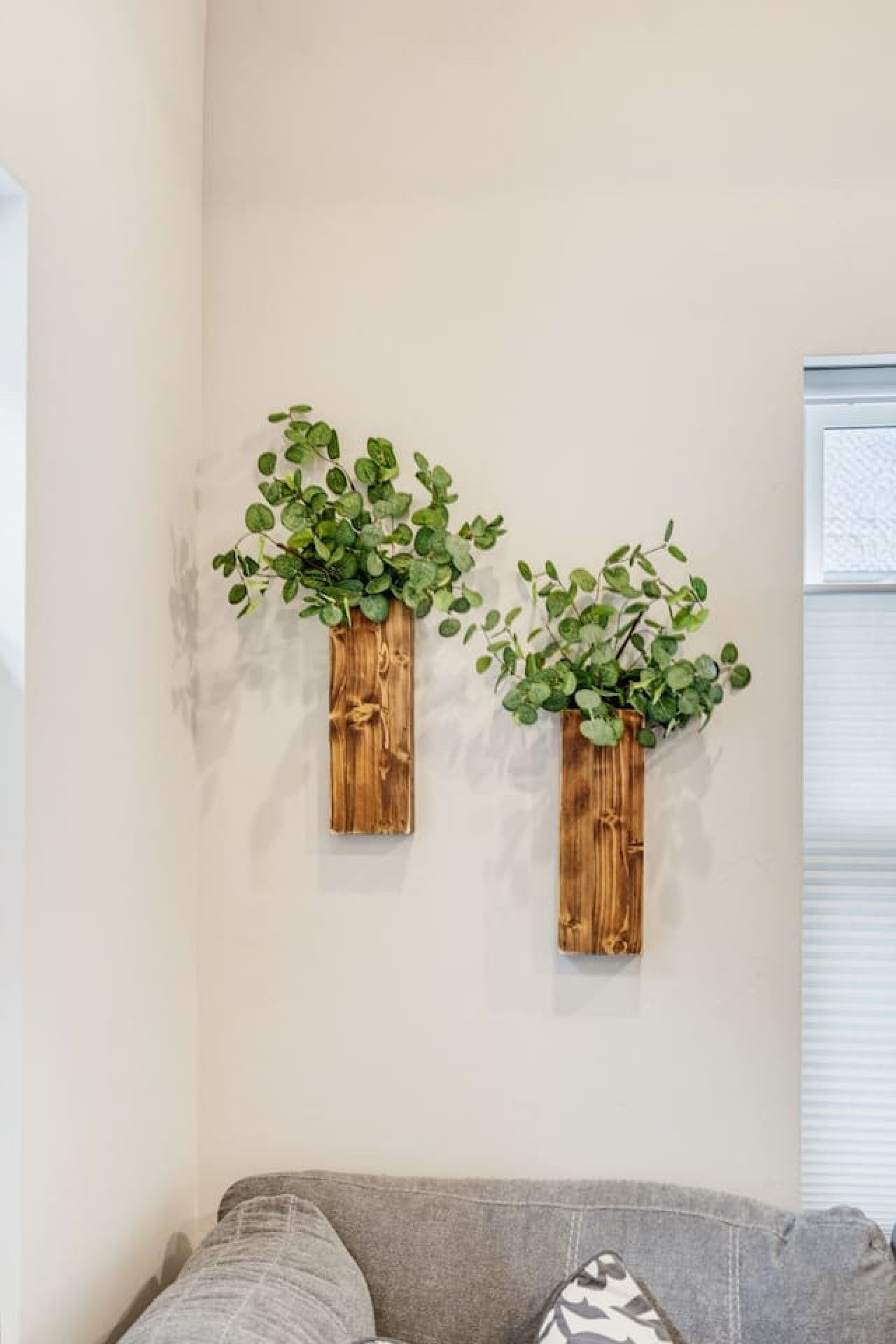 Two wooden planters with green foliage on a wall.