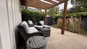Un patio al aire libre con mobiliario de mimbre, incluyendo dos sillones y una mesa.