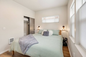 A bedroom with a bed, bedside lamps, a window with blinds, a closet, and a radiator. - Ashland Cottage | Walk to Downtown & Coffee (Ashland)