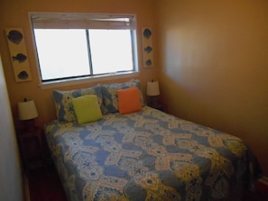 A bedroom with a bed, two bedside lamps, a window, and wall decorations. - A Place at the Beach (Isle of Palms)