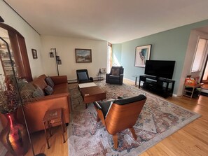 Un salon comprenant un canapé, un fauteuil, une table basse et un téléviseur à écran plat.