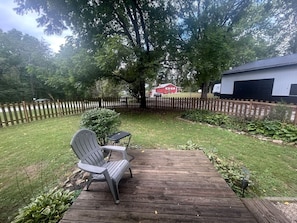 A wooden deck with two Adirondack chairs, a small table, and a red building in the background. - Portland Mills Ramp Drive (Greencastle)