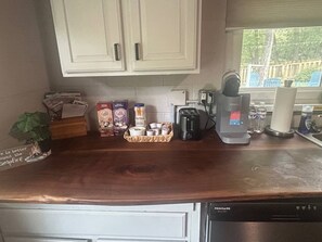 A kitchen with white cabinets, a coffee maker, a kettle, and various coffee products on the counter. - Portland Mills Ramp Drive (Greencastle)
