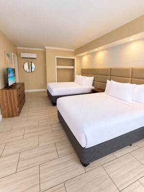 A hotel room with two beds, a wooden dresser, a round mirror, and a television. - The Sunny Seaside 300 Tenth | 102 (Myrtle Beach)