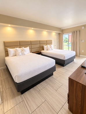 A hotel room with two beds, a wooden desk, and a view of the outdoors. - The Sunny Seaside 300 Tenth | 102 (Myrtle Beach)