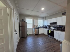 A kitchen with white cabinets, stainless steel appliances, and a wooden floor. - 2BR Apartment Near Wesleyan 303 (Middletown)