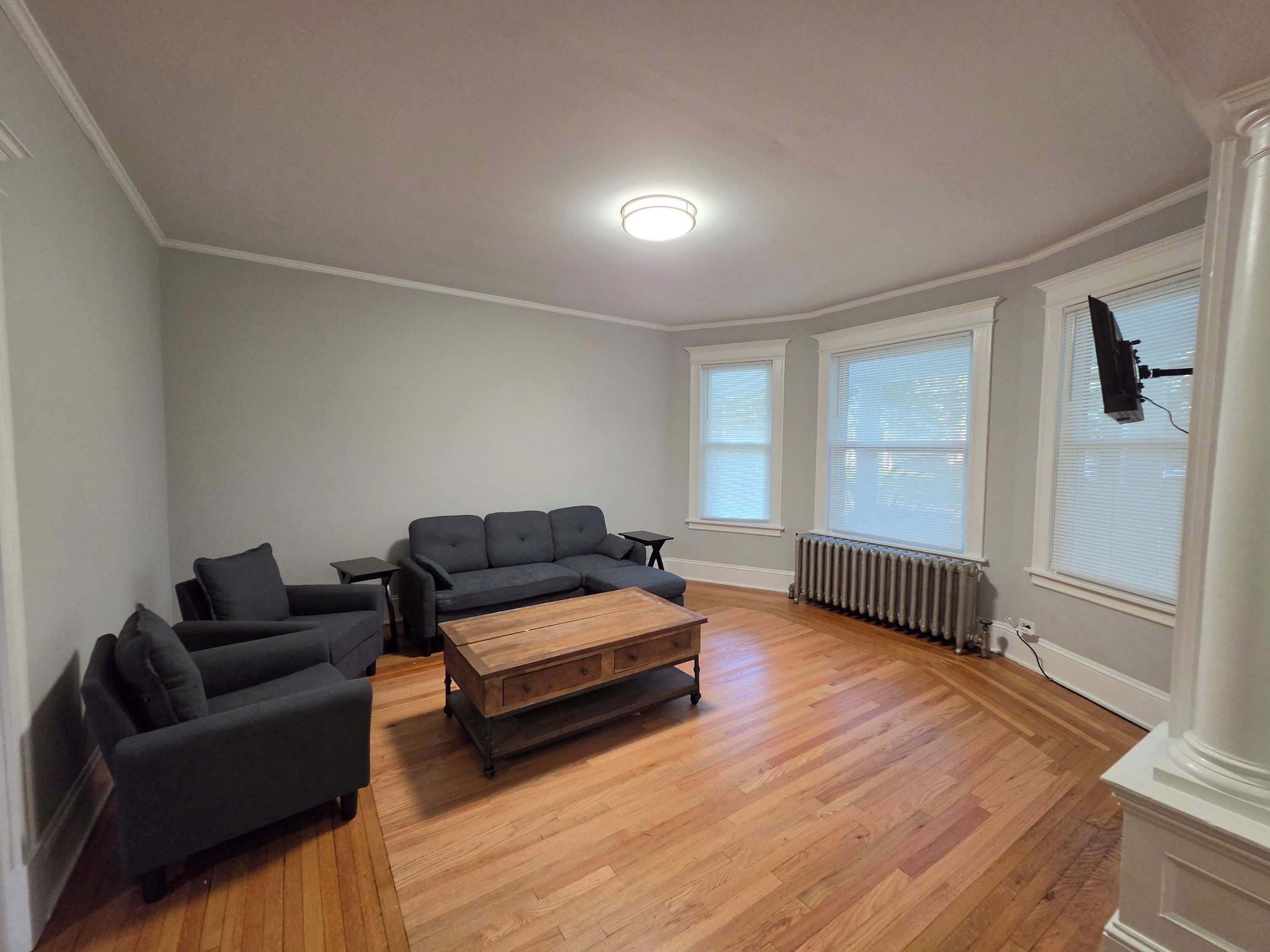 A living room with a sectional sofa, a coffee table, and a TV mounted on the wall.