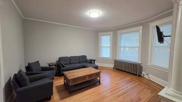 A living room with a sectional sofa, a coffee table, and a TV mounted on the wall.