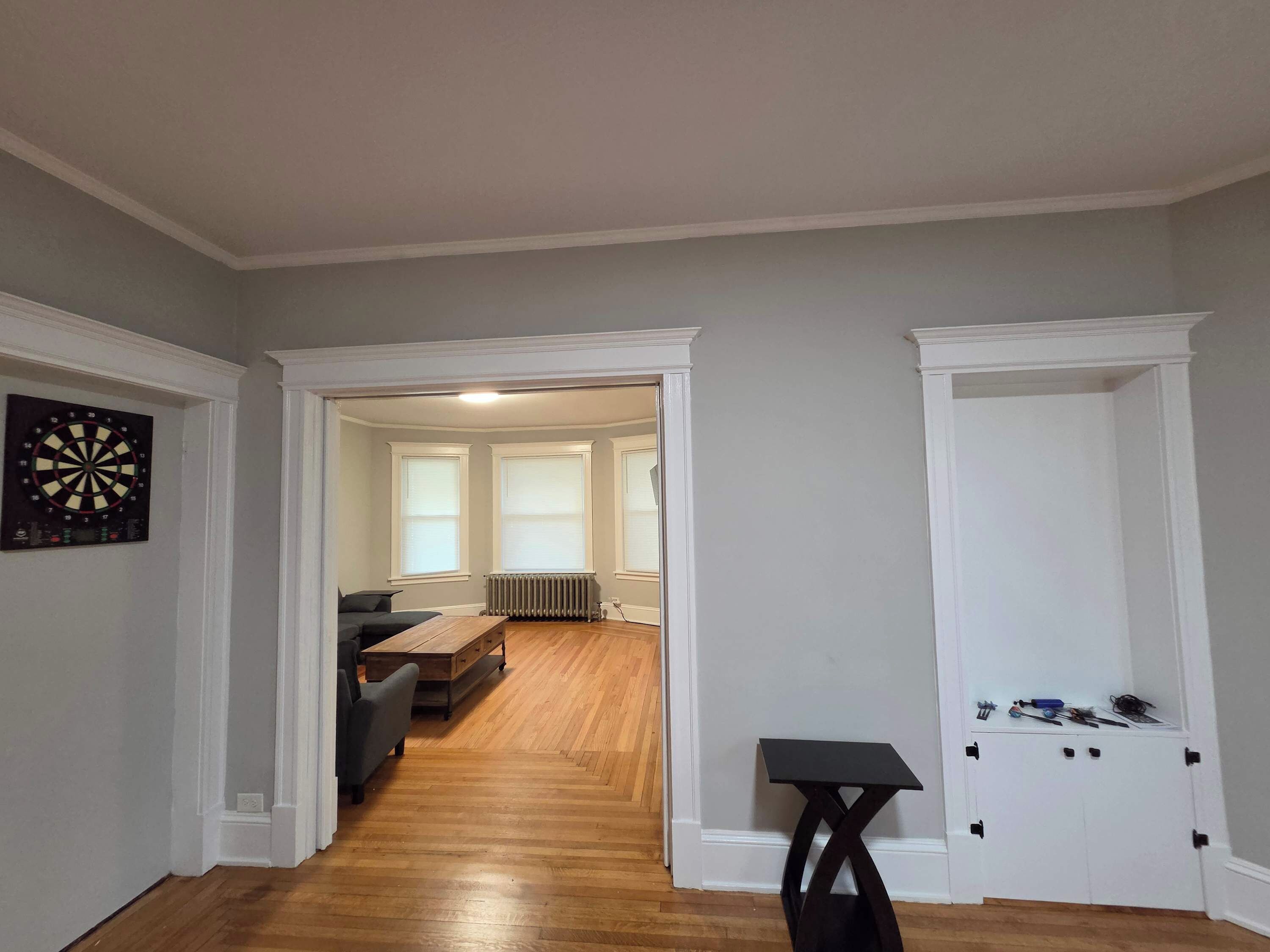 A hallway with a dartboard, a wooden table, and a small table with tools.