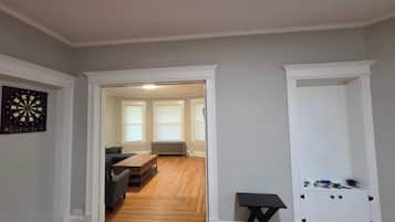 A hallway with a dartboard, a wooden table, and a small table with tools.