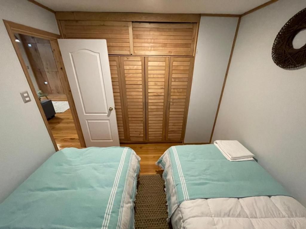 A bedroom with two beds, a wooden wardrobe, and a door leading to another room.