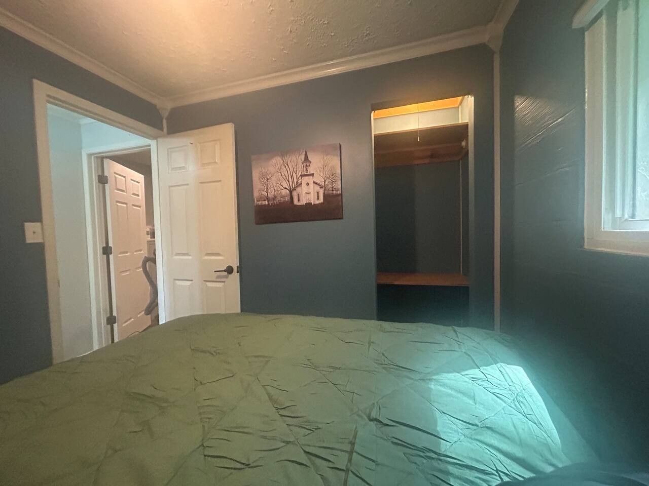 Une chambre à coucher avec un lit, une porte, une armoire et une fenêtre.