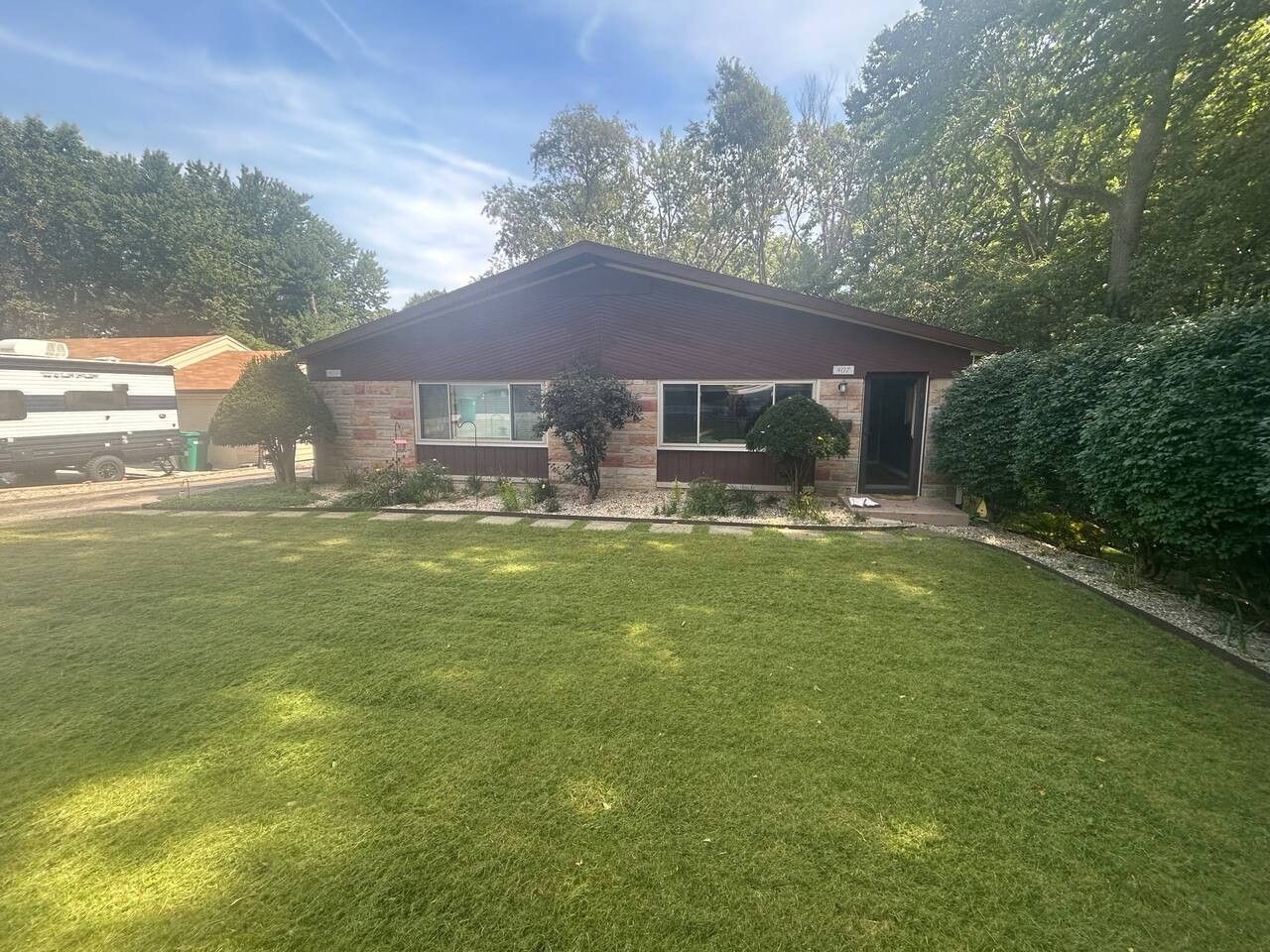 Une maison de plain-pied avec une pelouse devant, un garage et une allée.