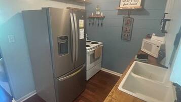 Une cuisine de taille réduite équipée d’un réfrigérateur, d’une cuisinière, d’un four à micro-ondes et d’un plan de travail en bois.