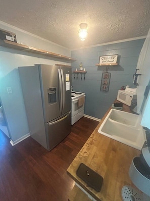 A compact kitchen with a refrigerator, stove, microwave, and a wooden countertop. - Danville Nature Nook (Danville)