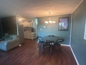 A dining area with a table and chairs, a kitchen in the background, and a living room with a couch. - Danville Nature Nook (Danville)