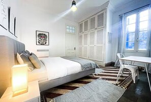 A bedroom with a bed, bedside table, chair, window, and wardrobe. - La Marsa Vibe (Tunis)