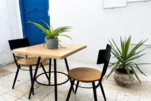 A small outdoor dining area with a wooden table and two chairs, a potted plant on the table, and another plant beside the table. - La Marsa Vibe (Tunis)