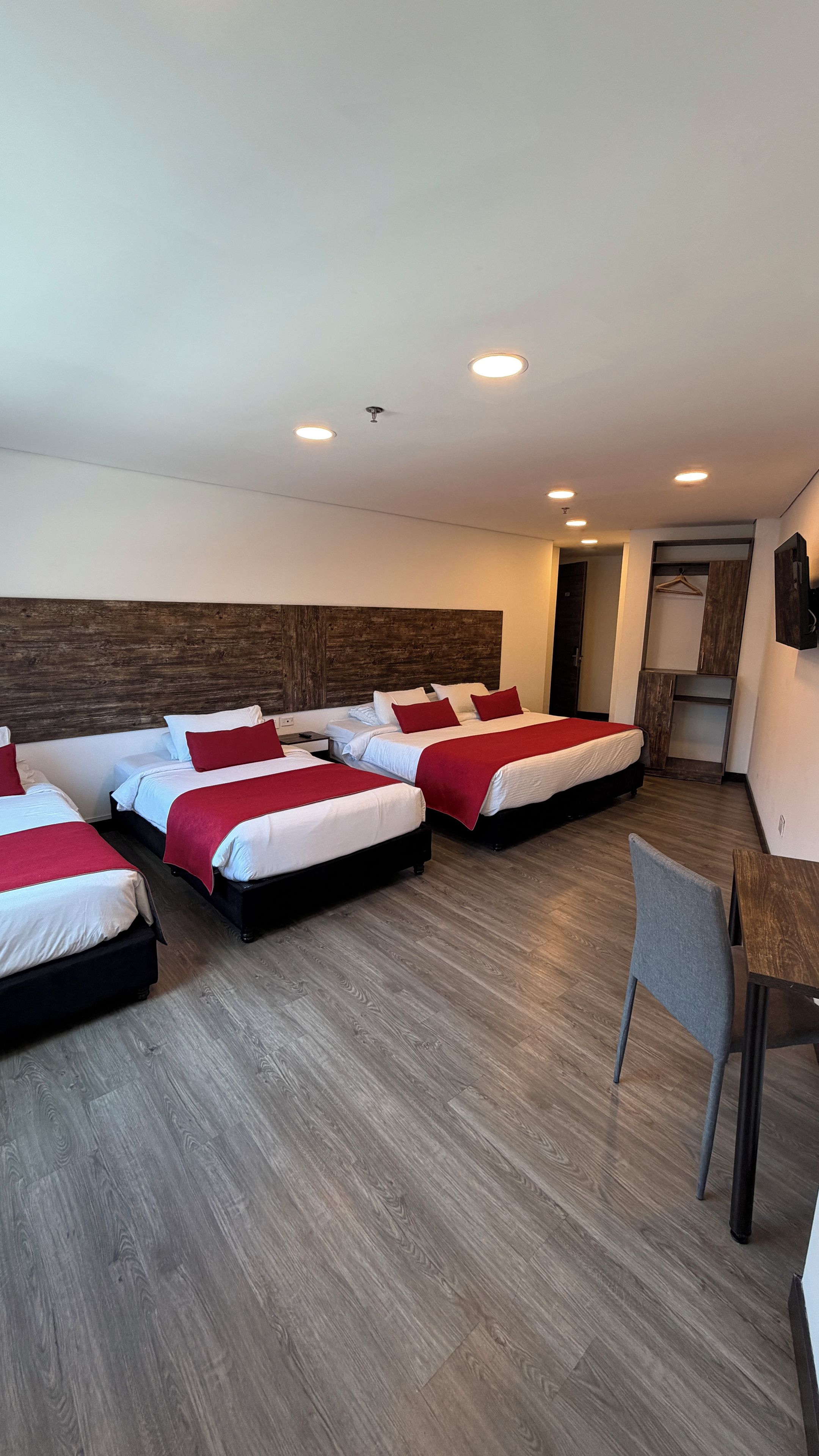 Een hotelkamer met vier bedden, een bureau en een stoel.