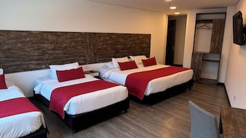 Een hotelkamer met vier bedden, een bureau en een stoel.