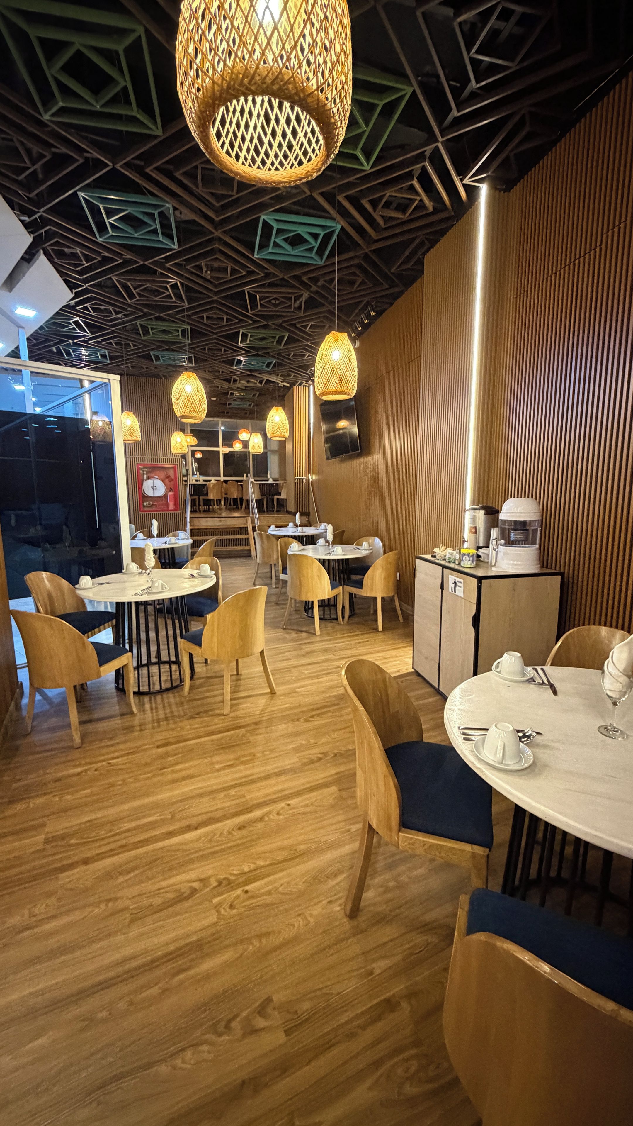 Een restaurantinterieur met houten vloeren, ronde tafels en stoelen.