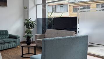 Een moderne woonkamer met een grijze bank, een groene fauteuil en een kleine tafel met een plant.