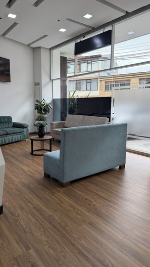 A modern living room with a grey sofa, a green armchair, and a small table with a plant. - Hotel WLH Ópalo (Bogotá)