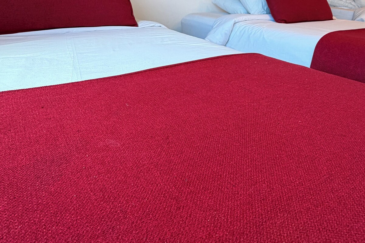 A hotel room with two beds, each with red and white bedding.