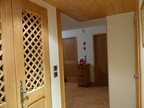 A wooden door with a lattice design, a hallway with a tiled floor, and a wooden cabinet with drawers. - Apartment with south-facing terrace - 4 guests (Crest-Voland)
