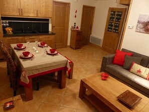 Ein Essbereich mit Tisch für vier Personen, einer Couch mit roten Kissen und einer Holzbank.