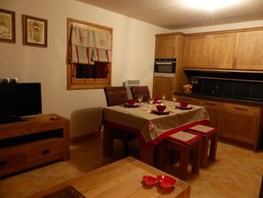 A dining area with a table set for four, a television, and wooden cabinets. - Apartment with south-facing terrace - 4 guests (Crest-Voland)