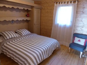A bedroom with a bed, a chair, a window with curtains, and a door. - Apartment with south-facing terrace - 4 guests (Crest-Voland)