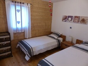 Ein Zimmer mit zwei Betten, einem Holzschrank und einer Wand mit Dekorationen.